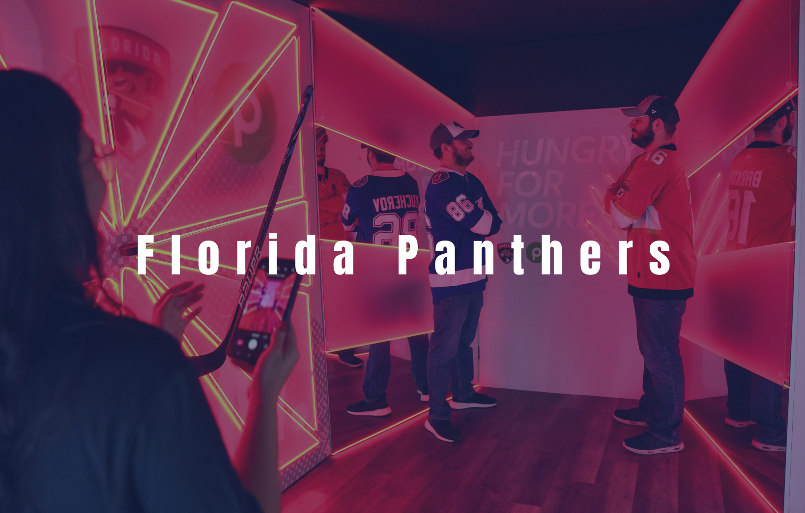 Attendees taking photos inside a Florida Panthers branded fan experience with red LED lighting.