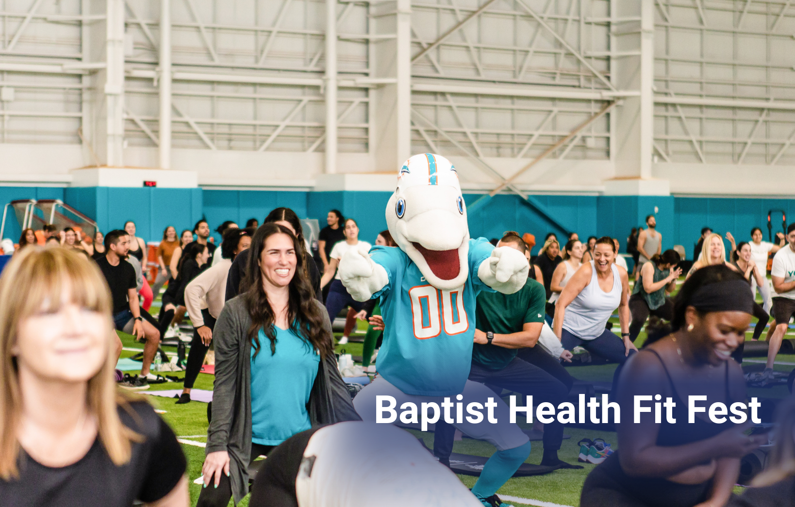 Crowd participating in a group fitness class at the Baptist Health Fit Fest with the team mascot leading the workout.