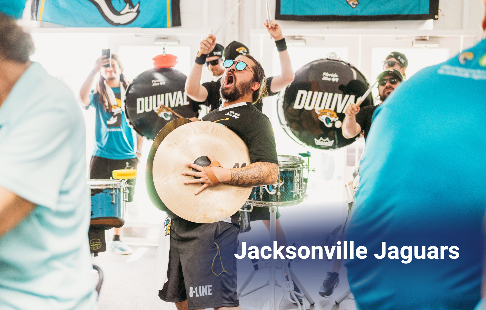 Jacksonville Jaguars drumline performing indoors with musicians playing cymbals and drums during a fan event.