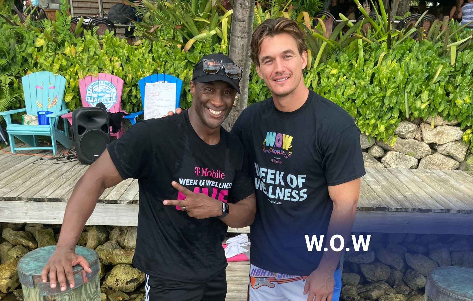 Two men smiling and posing together during an outdoor T-Mobile Week of Wellness event near a dockside setting.